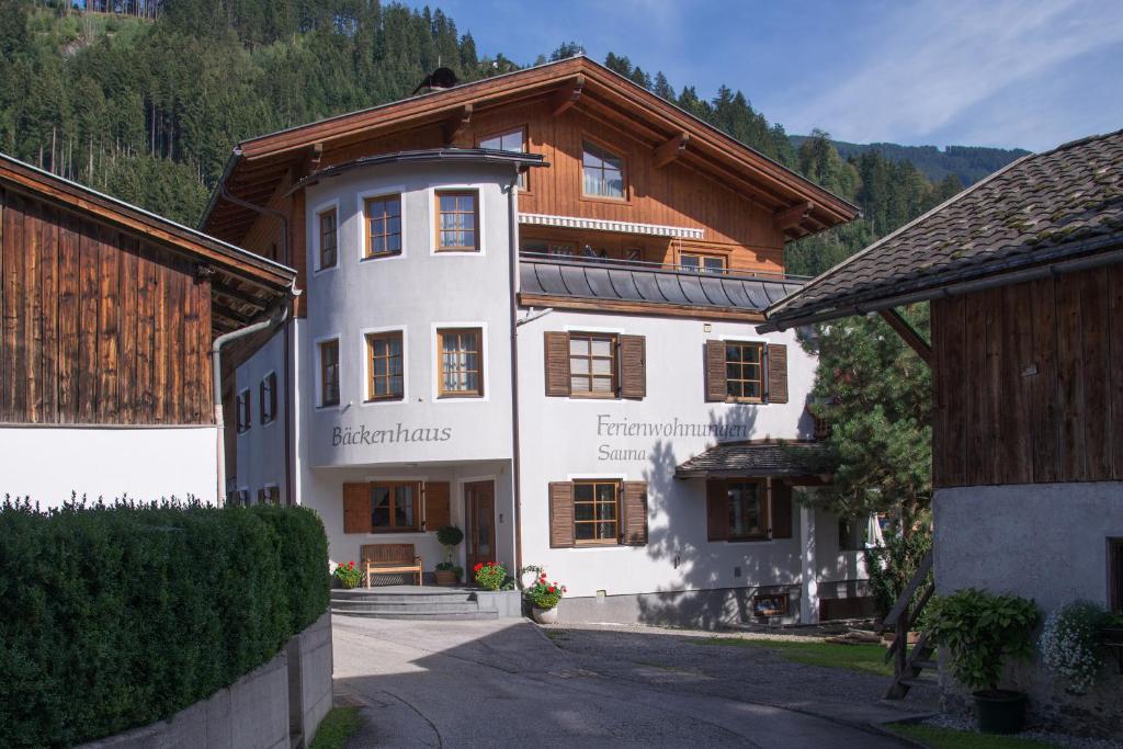 ein großes weißes Gebäude mit einem Holzdach in der Unterkunft Ferienwohnungen Bäckenhaus in Stumm