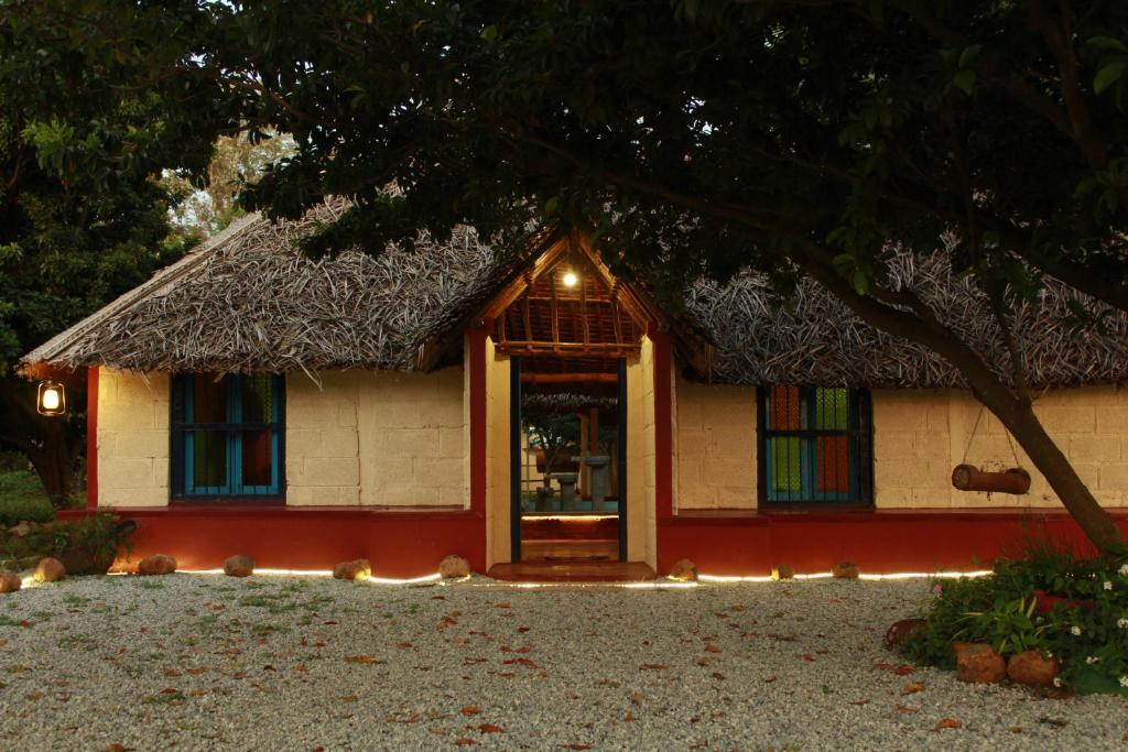 a small house with a thatch roof at Malgudi Farms in Bangalore