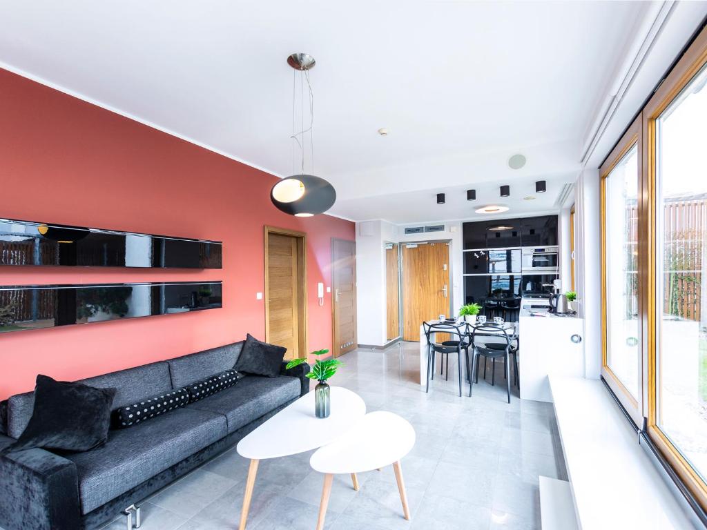 a living room with a black couch and a red wall at VacationClub - Olympic Park Apartment C606 z tarasem widokowym in Kołobrzeg