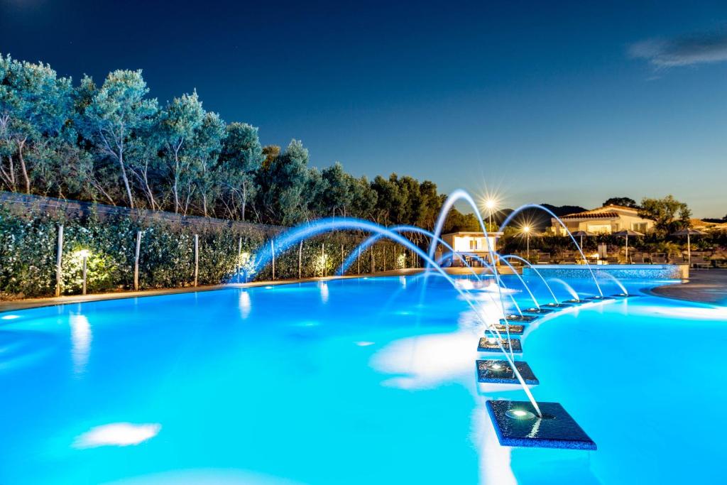uma grande piscina com água azul à noite em Ville D'Ogliastra em Cardedu