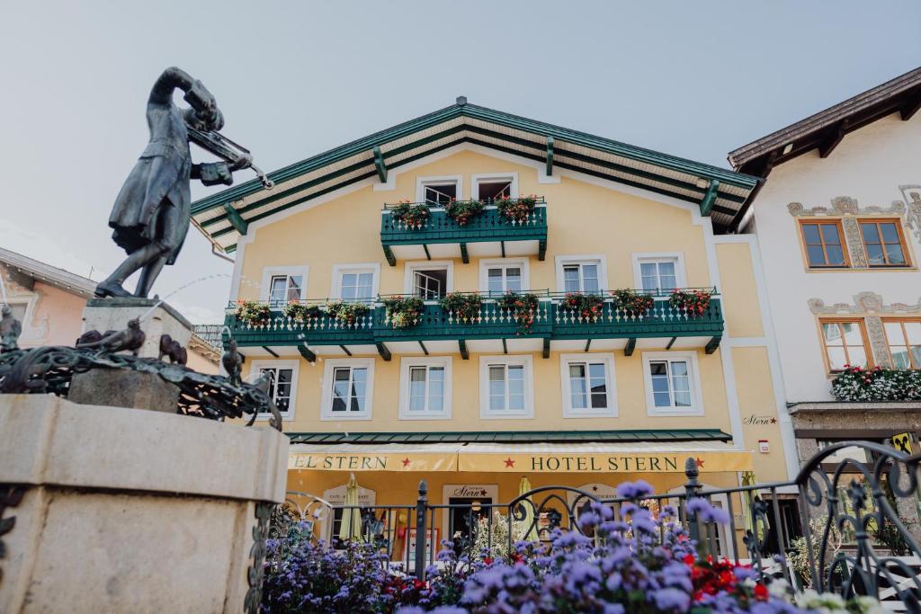 a hotel with a statue in front of a building at Das Hotel Stern 24h self-check-in in Sankt Gilgen