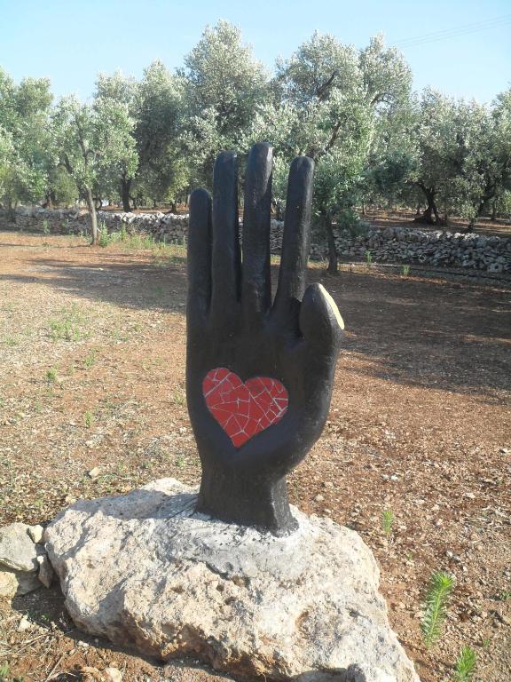 a statue of a hand with a heart on a rock at Case d'Artista in Savelletri di Fasano