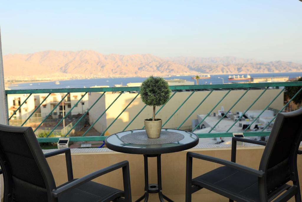 a table with a plant on a balcony with two chairs at נוף לים האדום - sea view eilat in Eilat