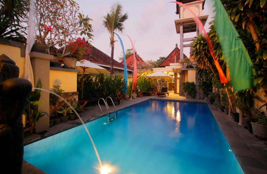 a swimming pool in front of a building with a hotel at Hotel Jati Sanur in Sanur