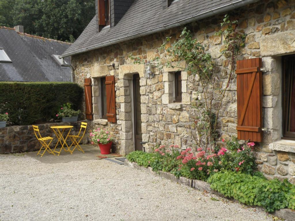 une maison en pierre avec une table, des chaises et des fleurs dans l'établissement Kerbaliou, à Crozon