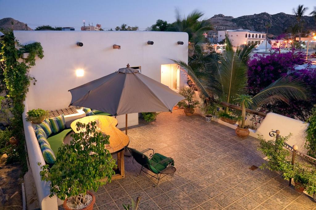 a patio with a couch and an umbrella at Los Milagros Hotel in Cabo San Lucas