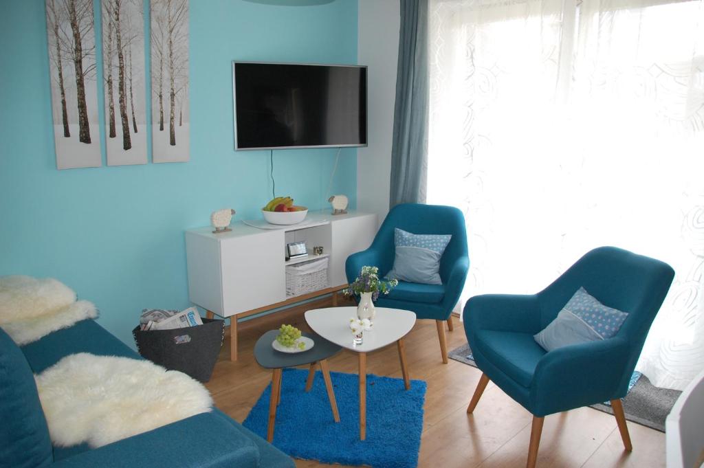 een woonkamer met twee blauwe stoelen en een televisie bij Ferienwohnung "EDELweiß" in Inzell