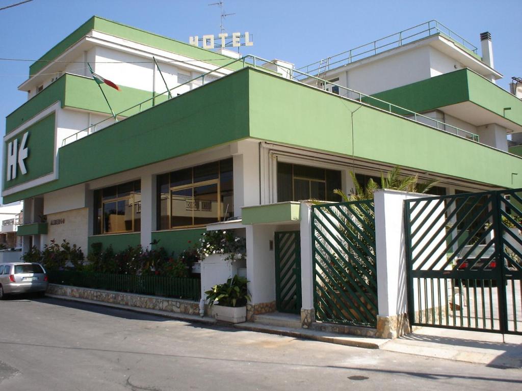 un bâtiment vert et blanc avec une voiture garée devant dans l'établissement Hotel Esperia, à Sammichele di Bari