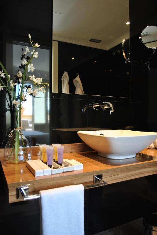 baño con lavabo y jarrón de flores en Hotel Sardinero Madrid, en Madrid