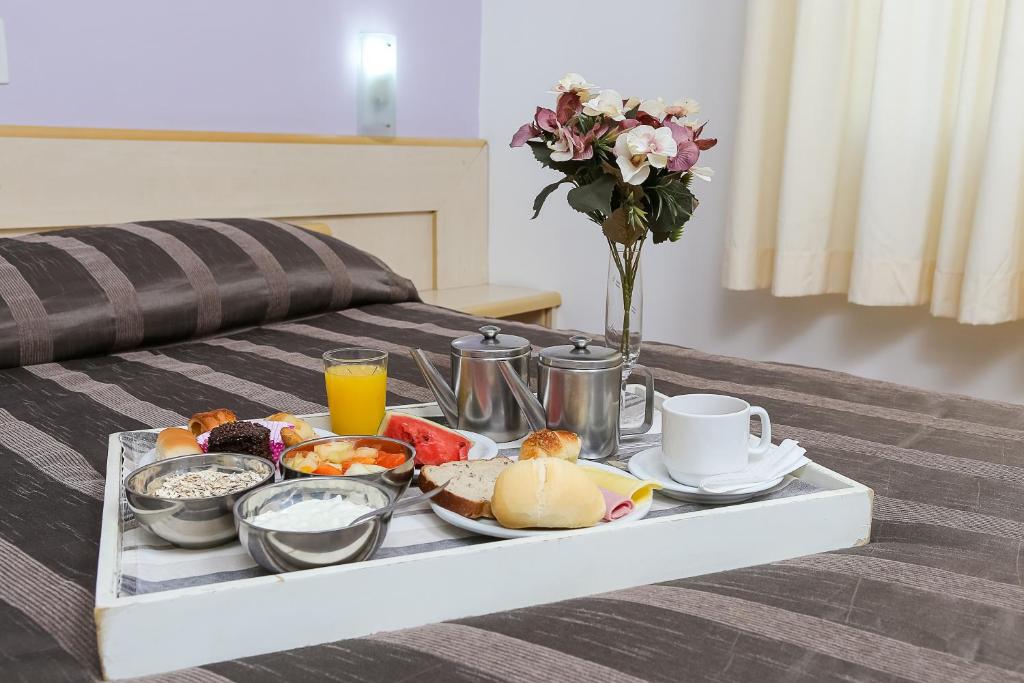 uma bandeja de alimentos de pequeno-almoço numa cama em Hotel Suárez São Leopoldo em São Leopoldo