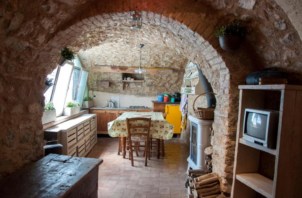a kitchen with an archway with a table and a television at Charming rustic house in Gardone Riviera