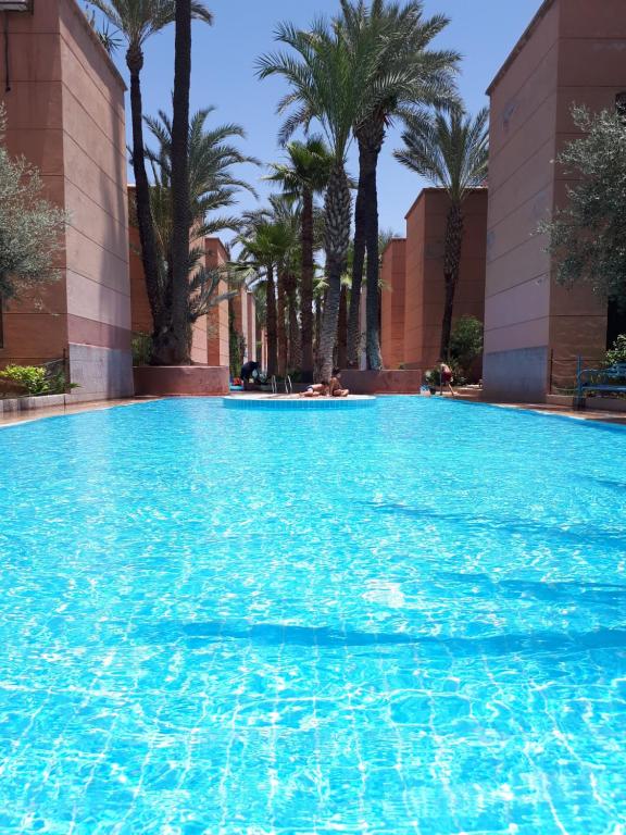 una gran piscina con palmeras en el fondo en Riad with 3 Swimming Pools, en Marrakech