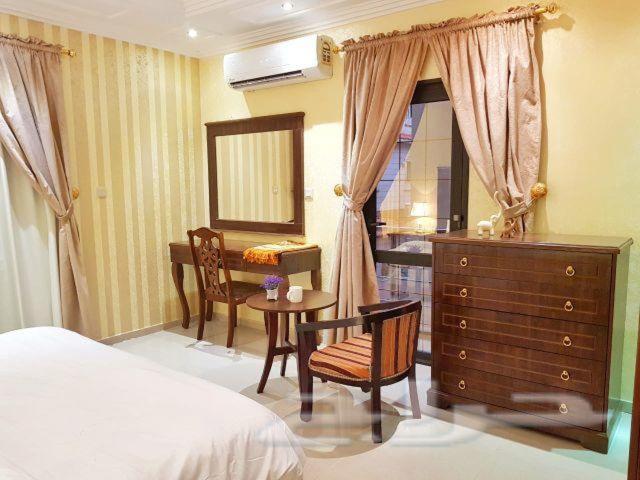 a bedroom with a bed and a dresser and a desk at Nadra Furnished Apartments in Taif
