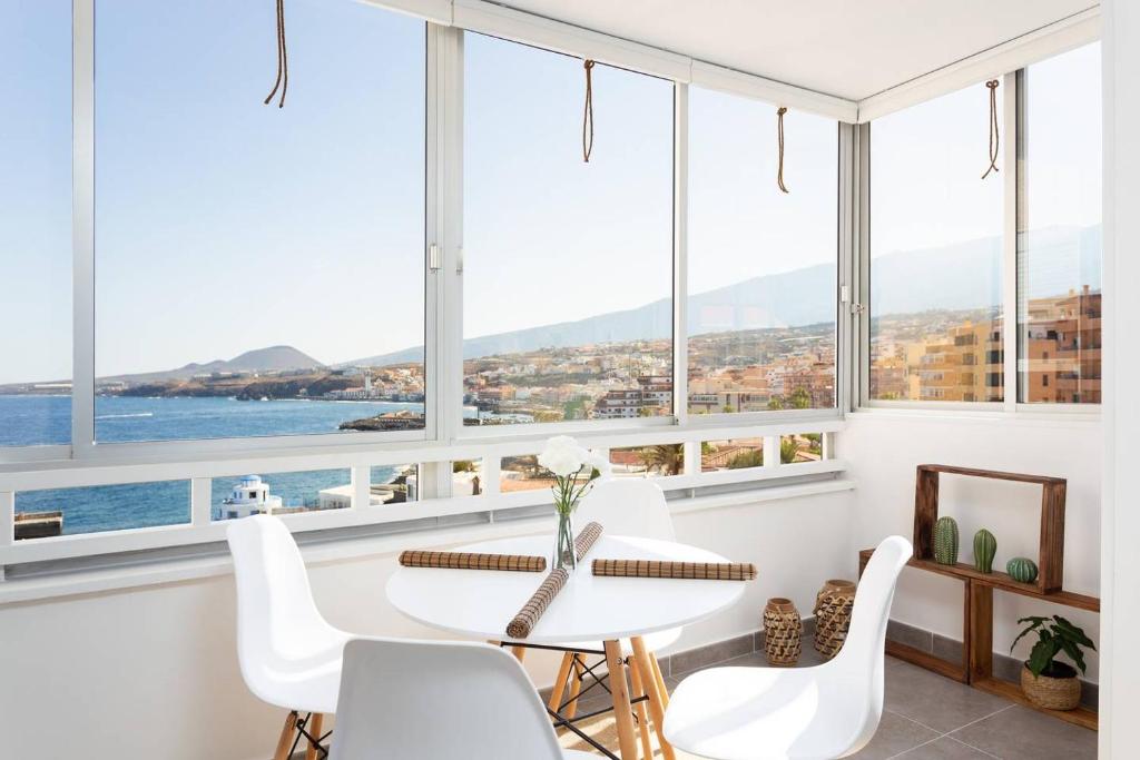 a dining room with a table and chairs and windows at El Faro: vistas panorámicas y ubicación perfecta in Candelaria