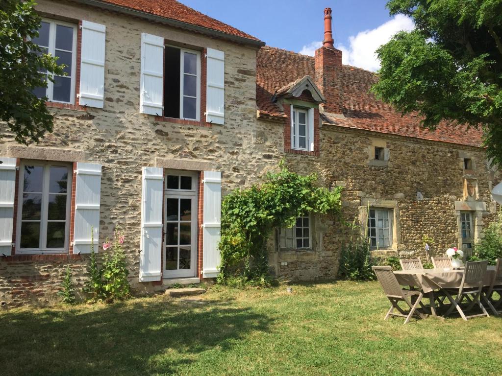 an old stone house with a picnic table in the yard at La Motte in Louroux-de-Bouble