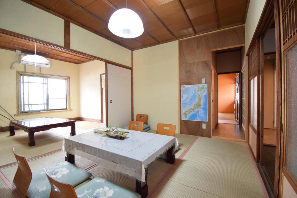 sala de estar con mesa, sillas y piano en Bed&Bicycle, en Kashihara