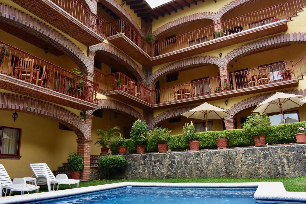 un edificio de apartamentos con piscina, mesas y sillas en Posada Rincon Magico, en Tepoztlán
