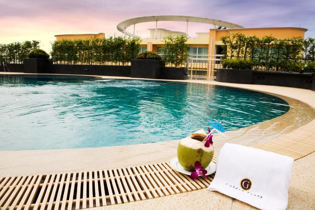eine Kokosnuss auf einer Bank neben einem Pool in der Unterkunft Golden Pearl Hotel in Bangkok
