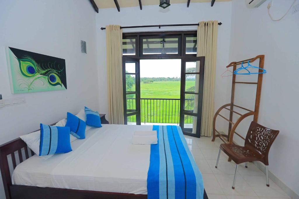 a bedroom with a bed and a chair and a window at Serene View Tourist Rest in Anuradhapura