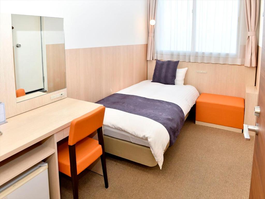 a small room with a bed and a desk and a mirror at New Commander Hotel Osaka Neyagawa in Neyagawa