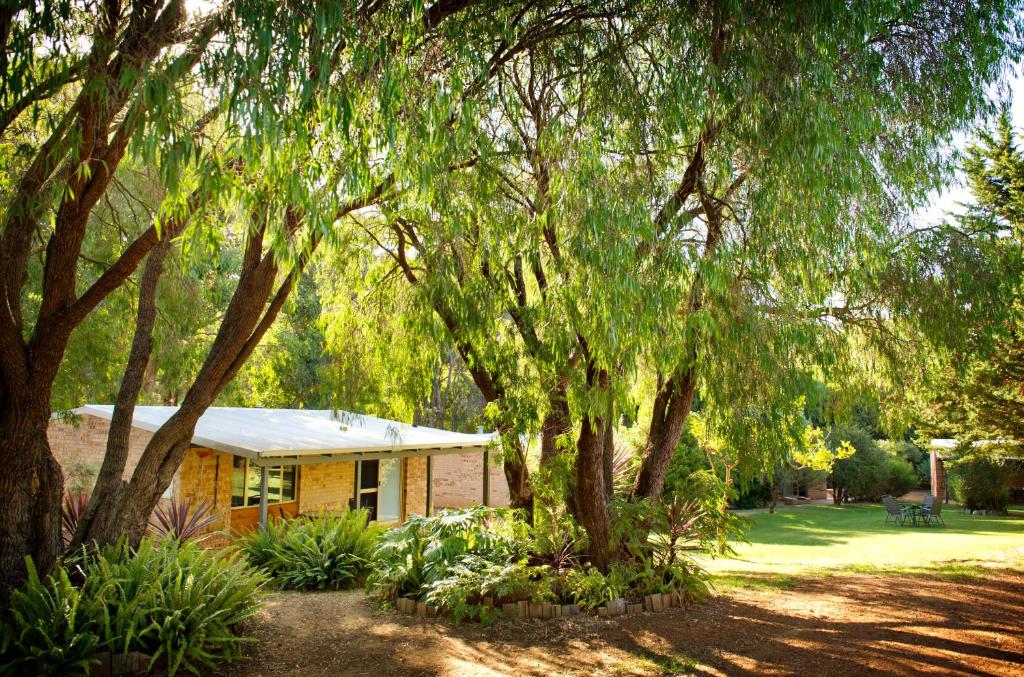 a yellow house with trees in front of it at Peppermint Brook Cottages in Margaret River Town