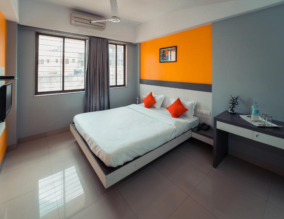 1 dormitorio con 1 cama con paredes de color naranja y escritorio en Hotel Aashish Deluxe Pet Friendly, en Kolhapur