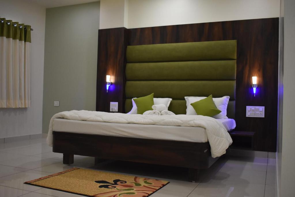 a bedroom with a large bed with a green headboard at Hotel Shyam Palace in Bhuj