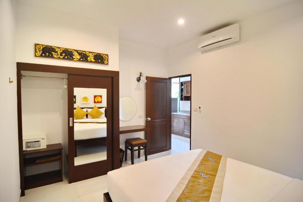 a bedroom with a bed and a mirror and a room at Arthaya Villas - SHA Extra Plus in Ko Lanta