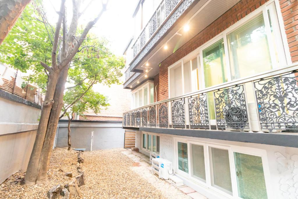 Dawoo House 1 in Hongdae في سول: عمارة سكنية مع شرفة وشجرة