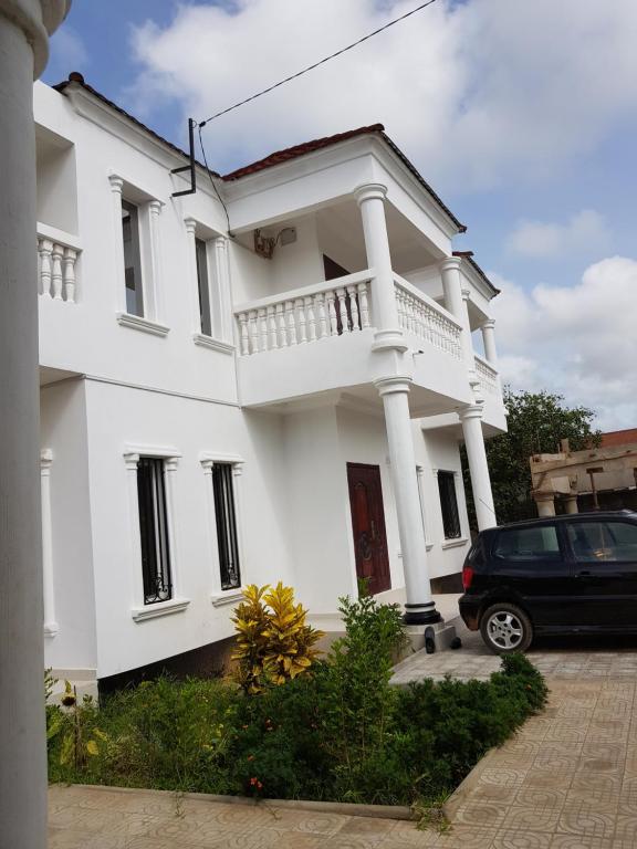 a white house with a car parked in front of it at Heather's Retreat in Brufut