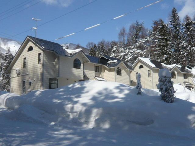 a house with a pile of snow in front of it at Hakuba Royal Suites in Hakuba