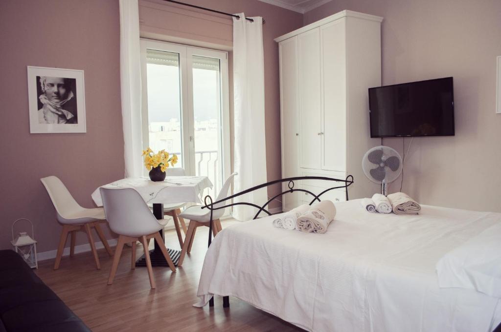 una camera con due letti, un tavolo e una finestra di Casa Giulia a Cagliari