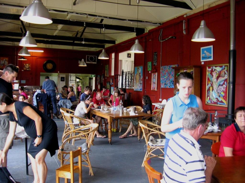 a group of people sitting at tables in a restaurant at Bowral Road Art Gallery Bed and Breakfast in Mittagong