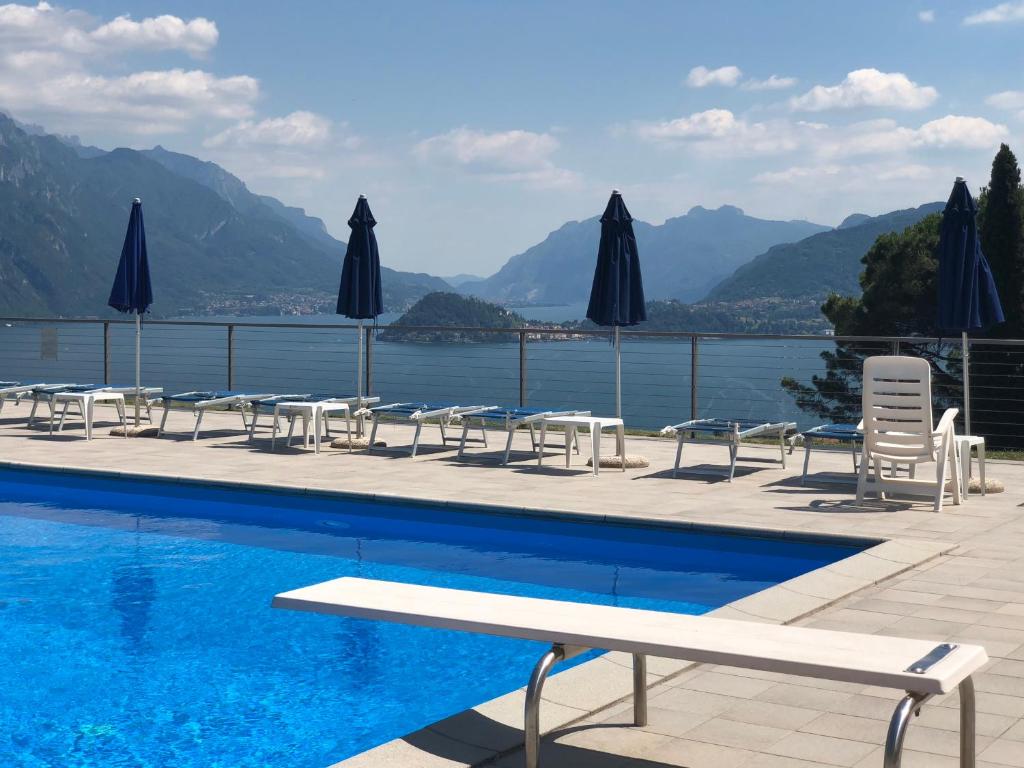 a pool with chairs and umbrellas next to the water at Terrazze - Luxury Lake Como View Apartment - in Menaggio in Menaggio