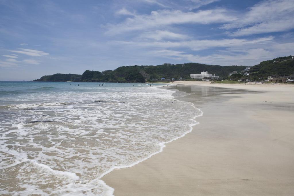 a beach with the ocean and people in the water at Hotel Izukyu in Shimoda
