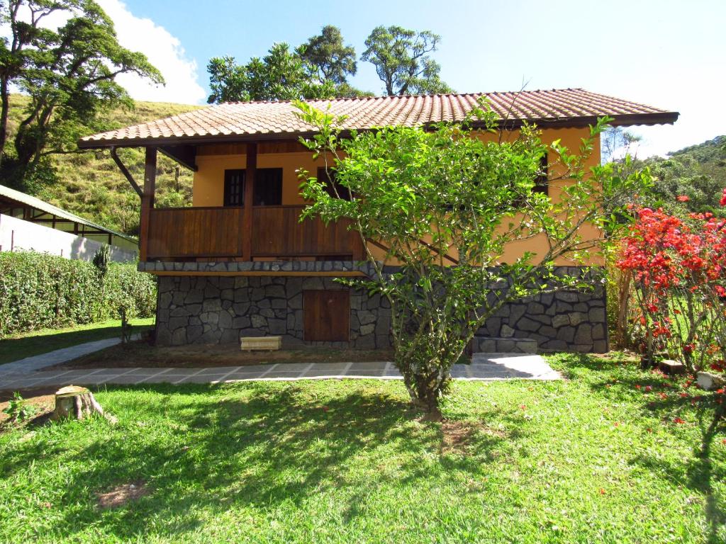 uma pequena casa com uma árvore no quintal em Chalé Caminho Das Cachoeiras em Visconde de Mauá
