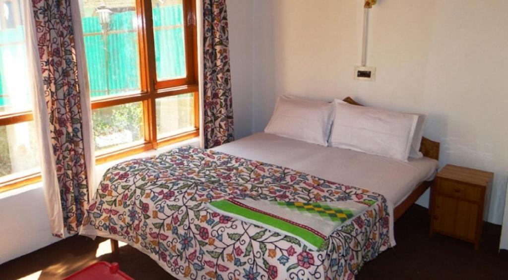 a bedroom with a bed and a window at Hayat Hotel Pahalgam in Pahalgām