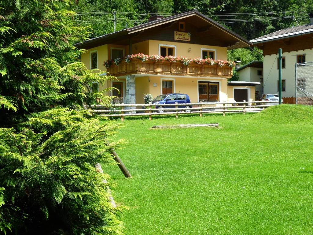 ein gelbes Haus mit Balkon auf einem Hof in der Unterkunft Vronis Landhaus Apartments in Hüttau