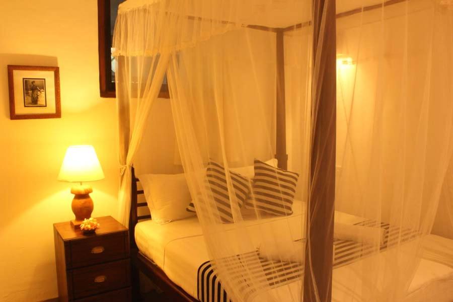 a bedroom with a canopy bed with white curtains at Pedlar 62 Guest House in Galle