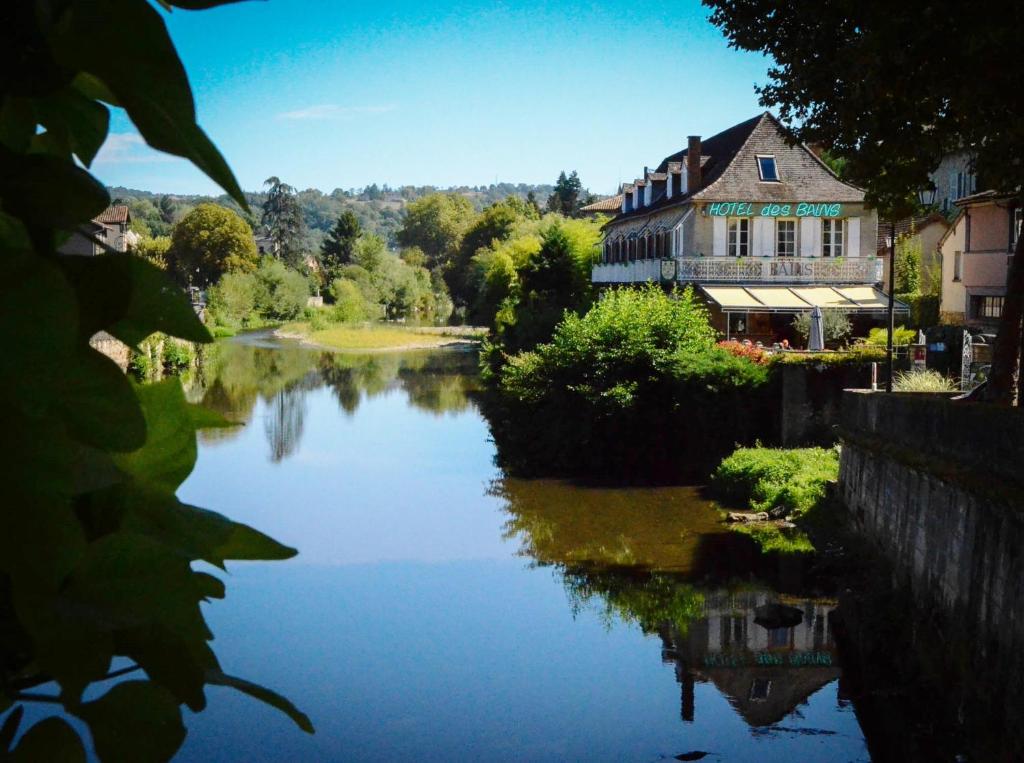 a river in front of a house and a building at Hôtel des Bains in Figeac