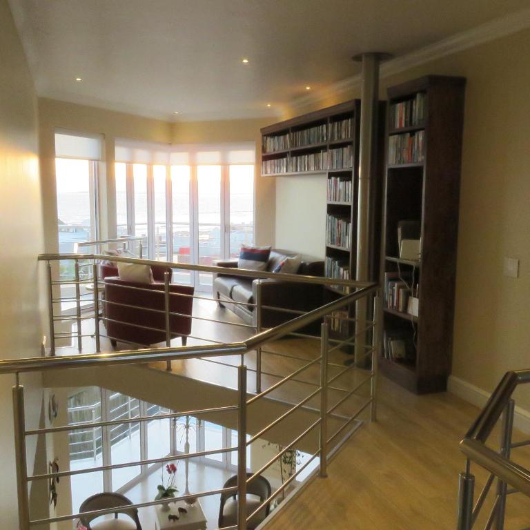 a living room with couches and bookshelves at Gull on the Bay Boutique Guest House in Bloubergstrand