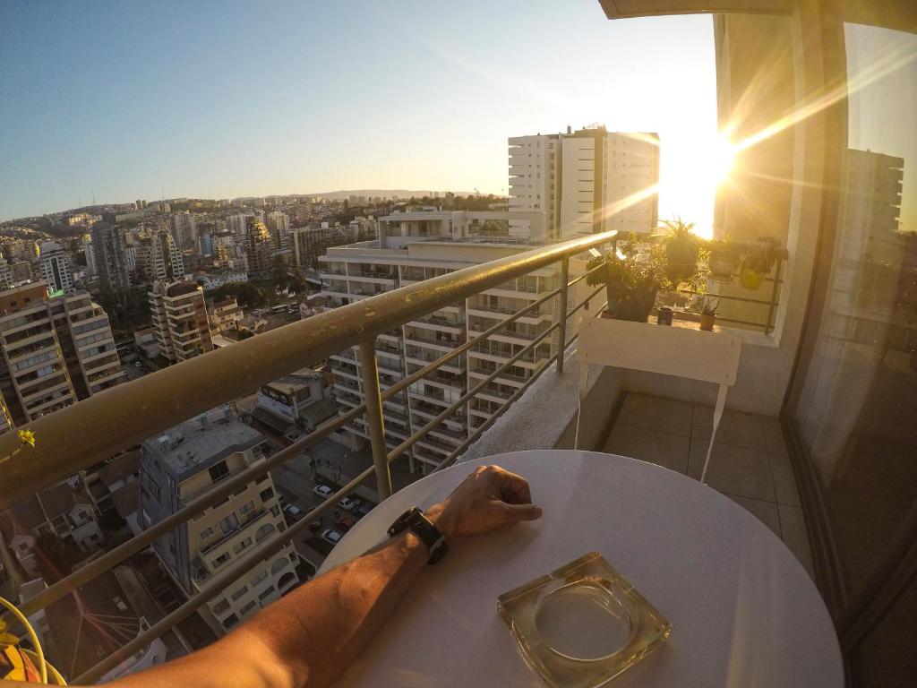 una persona sentada en una mesa sobre un balcón en Marina Poniente Apartment en Viña del Mar