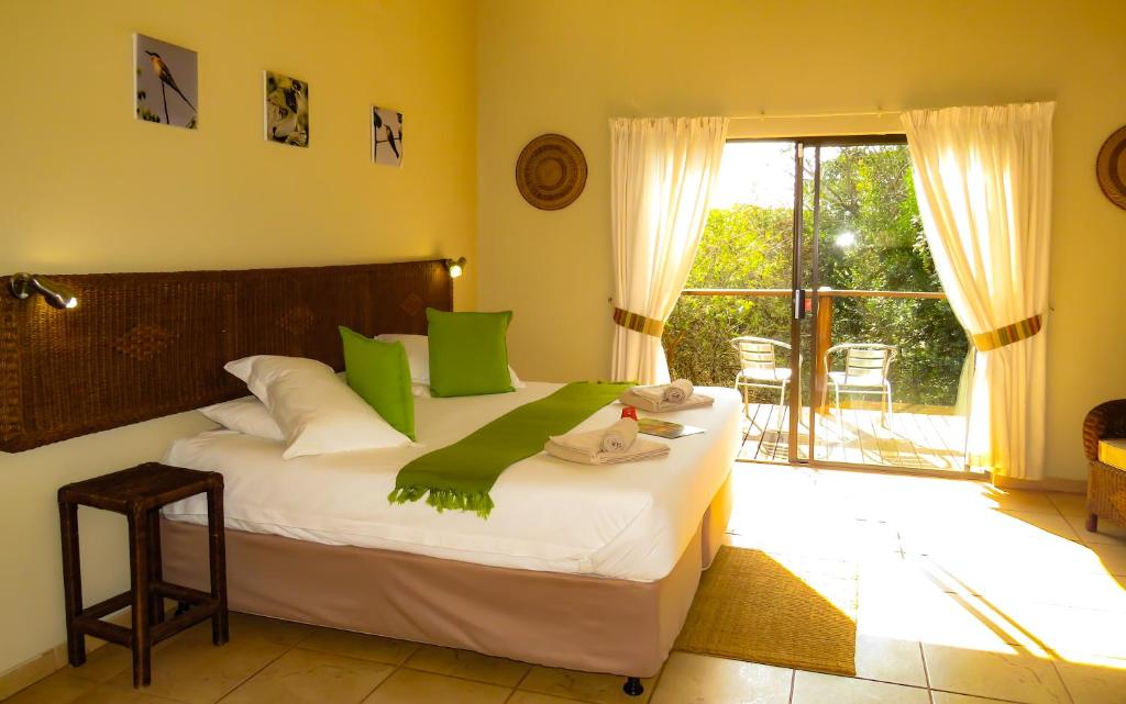 a bedroom with a large bed with green pillows at Umkhumbi Lodge in Hluhluwe