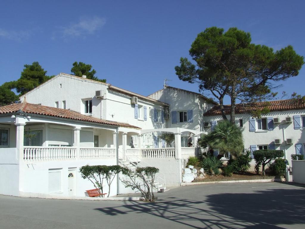une maison blanche avec un arbre en face dans l'établissement Le Sarac Hôtel, à Clermont-lʼHérault