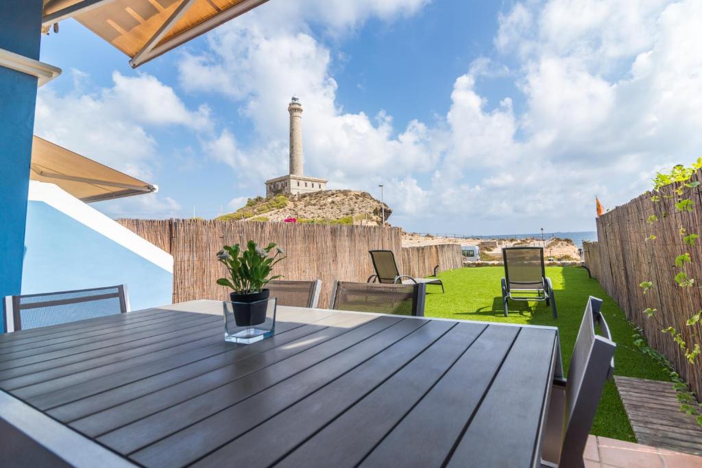 una mesa de madera en un patio con un faro en el fondo en Urbanización Cala fría (Faro Cabo de Palos) en Cabo de Palos