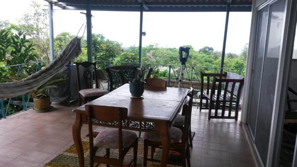 eine Veranda mit einem Holztisch und Stühlen auf dem Balkon in der Unterkunft Lita's Place in Cordillera Arriba
