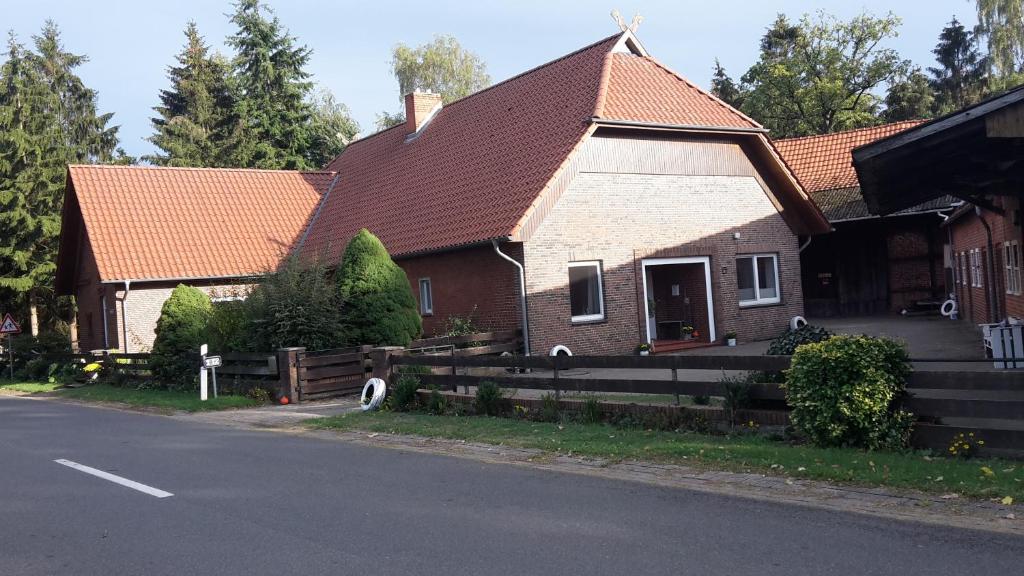 una casa con techo rojo y valla en Fremdenzimmer Buchholz en Groß Sehlingen
