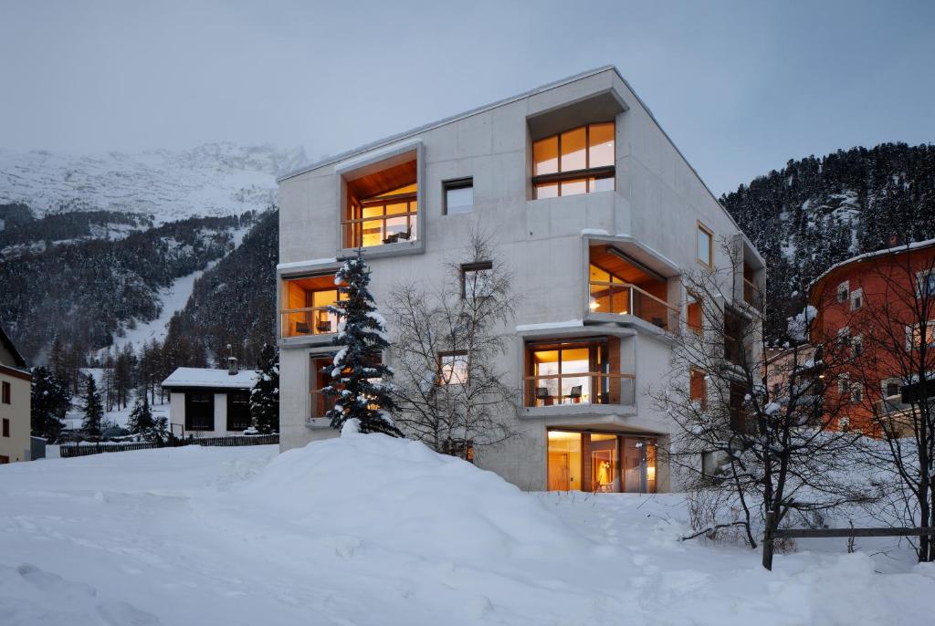 a building in the snow with a christmas tree at Alpine Lodge Chesa Plattner in Pontresina