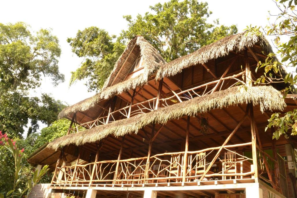 a building with a straw roof with trees in the background at Hostal Pakay in Tena