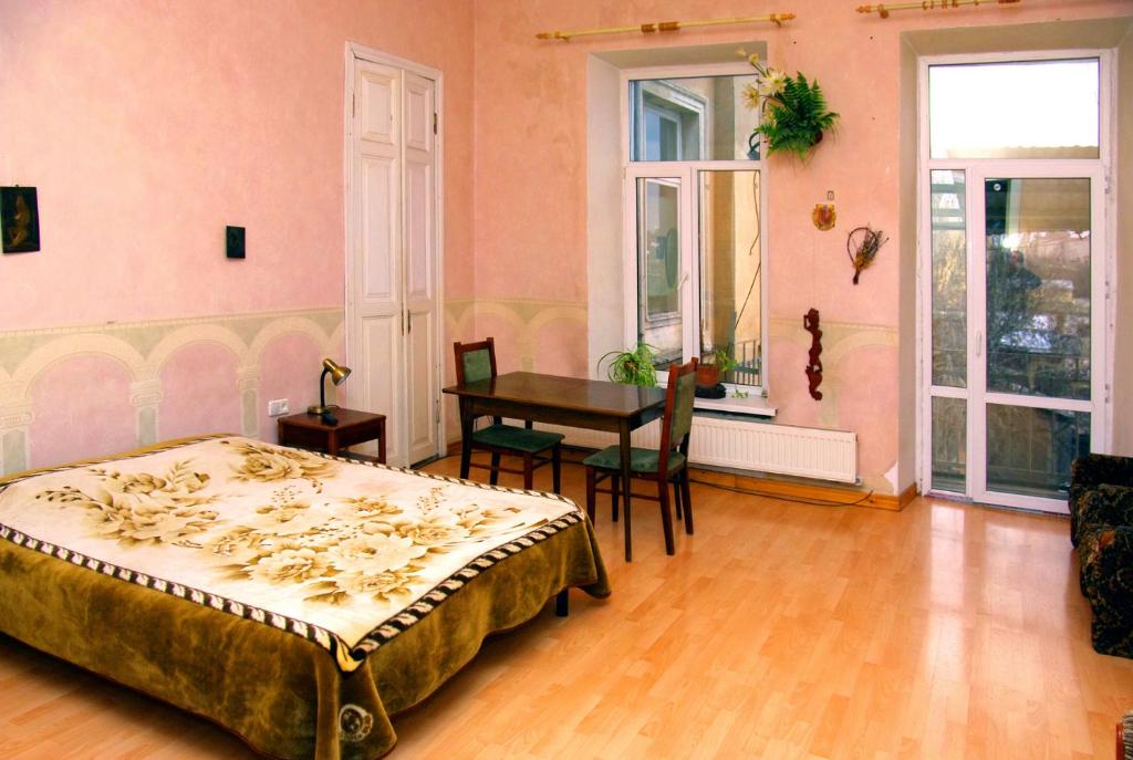 sypialnia z łóżkiem, stołem i oknami w obiekcie Большая комната w Odessie